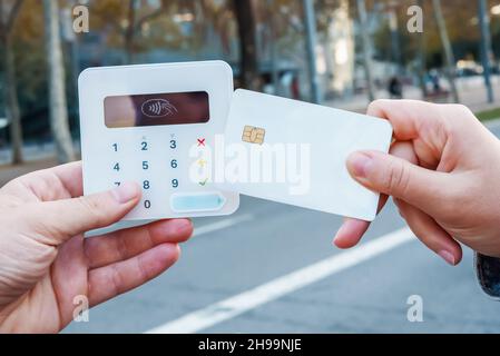 Crop unrecognizable female buyer with plastic card making contactless purchase on POS terminal in city street Stock Photo