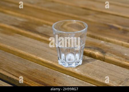 The glass that is almost empty stands on a wooden table. Milk has already been drunk, there is very little left on the bottom. Stock Photo