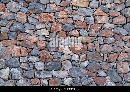 Textured background of masonry walls made of natural multicolored stones. Stock Photo