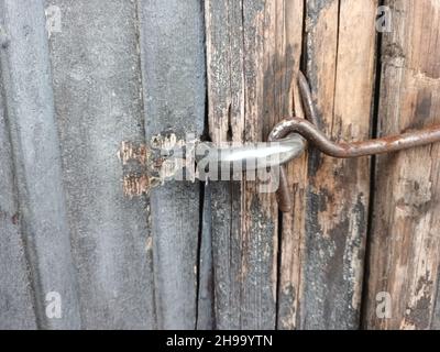 rusty old hook on weathered wooden barn door. Stock Photo
