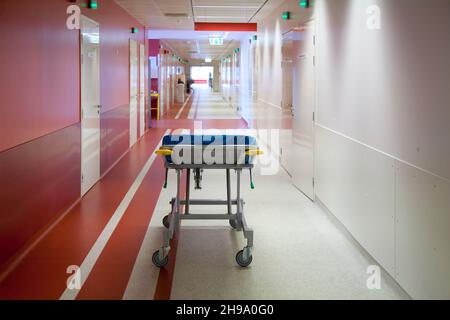 Corridor and waiting areas of a modern hospital with seating, a trolley bed wih blue mattress Stock Photo