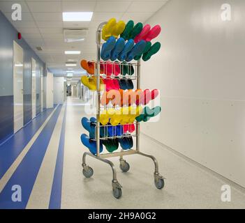 Corridor and waiting areas of a modern hospital, a rack with colourful surgical clogs. Stock Photo