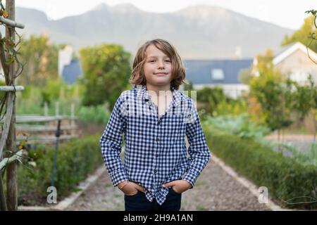 Portrait of eight year old boy smiling, hands in his pockets Stock Photo
