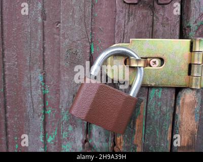 Hanging padlock on locked old wooden door. Stock Photo