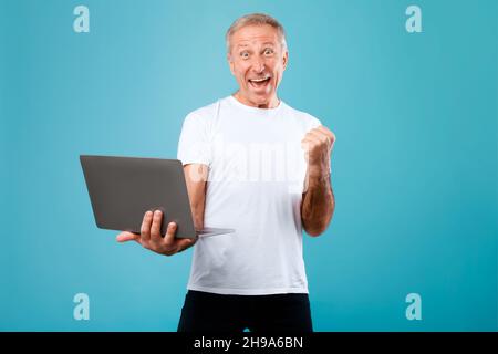 Cheerful mature man using laptop gesturing yes Stock Photo