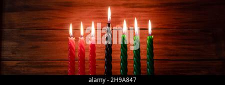 Celebration of African American Kwanzaa festival. Seven burning candles red, black and green in traditional Kinara candlestick. Symbols of African her Stock Photo