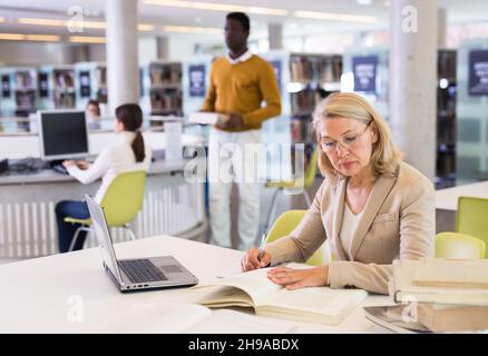 Mature teacher engaged in a public library Stock Photo - Alamy