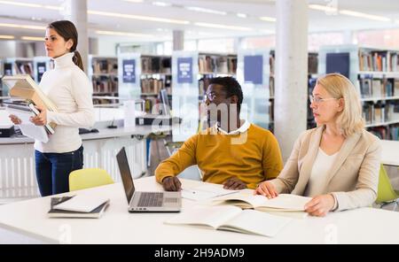 Teacher and adult students talking in the library Stock Photo