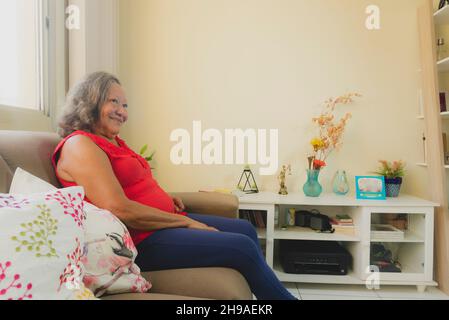 Portrait of a woman sitting on the sofa inside an apartment. Salvador, Bahia, Brazil. Stock Photo