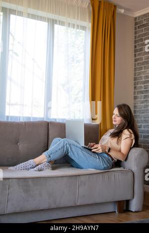 Comfortable work from home. A young woman is working remotely with a laptop. Stock Photo