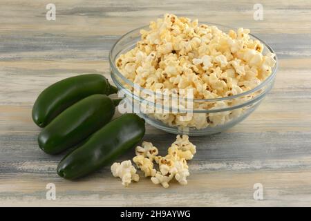 Jalapeno pepper flavored popcorn in glass snack bowl with fresh jalapenos Stock Photo
