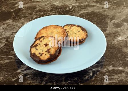 Three cocoa chocolate filled oat cookies on blue snack plate Stock Photo