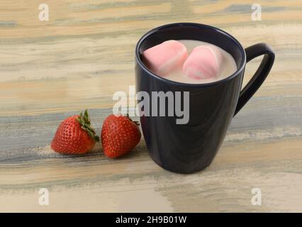 Hot white chocolate with pink strawberry marshmallows in blue mug with fresh strawberries Stock Photo