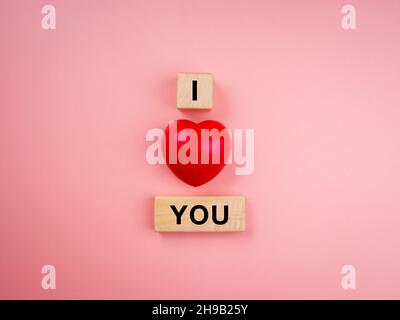 I love you, text on wooden cube block and red heart balloon on pink pastel background. Love concept minimal style. Stock Photo