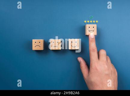 Customer service evaluation, ratings, feedback, client experience, and satisfaction survey concepts. Checkmark at five stars and hand pointing at happ Stock Photo