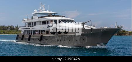 Nassau, Bahamas - May 14, 2019: Luxurious yacht Loon sailing in Nassau harbour. Some crew members on open decks. Turquoise water in the foreground. Sh Stock Photo