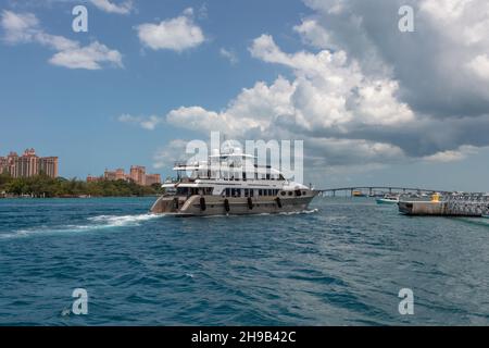 Nassau, Bahamas - May 14, 2019: Luxurious yacht Loon sailing in Nassau harbour.Turquoise water in the foreground. Atlantis resort, blue cloudy sky in Stock Photo