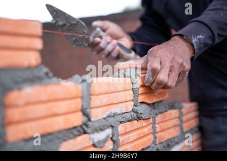 A hand of construction worker, industrial bricklayer installing bricks on construction site. Stock Photo