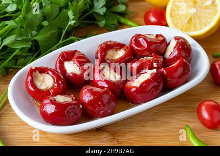 Cheese filled cherry peppers on wooden background. Local name peynir dolgulu kiraz biberi Stock Photo