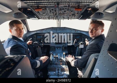 Two pilots sitting in cockpit and looking at camera Stock Photo