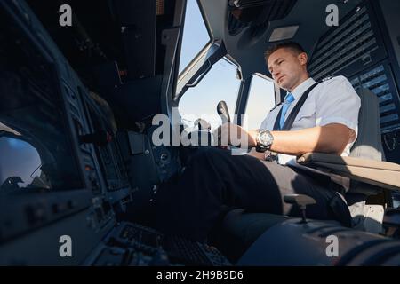 Side view of male co-pilot using control handle in cockpit for steering an airplane Stock Photo