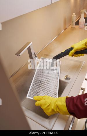 Cropped photo of cleaner in rubber gloves cleaning and disinfecting dirty part of kitchen air purifier Stock Photo