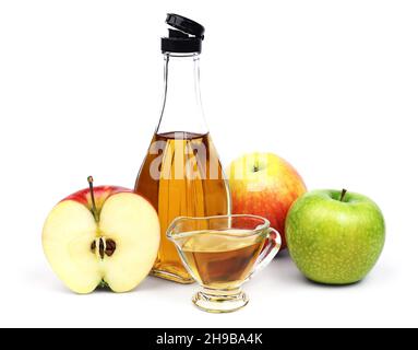 The open transparent full bottle and cup of Apple cider vinegar and a few different varieties of apples isolated on a white background. Stock Photo
