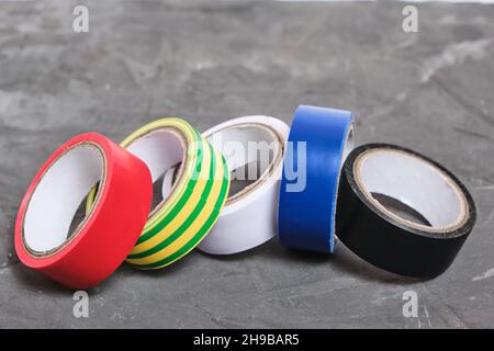 Set of multicolored insulating adhesive tape on a concrete background Stock Photo