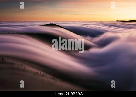 Mountain landscape above clouds at sunset in Slovakia with forest and sun Stock Photo