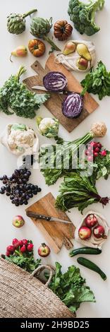 Table with fresh seasonal vegetables, greens, fruit, vertical composition Stock Photo