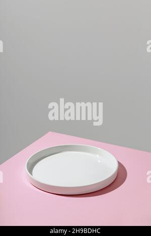 Empty plate with shadow on pink background. Copyspace  Stock Photo