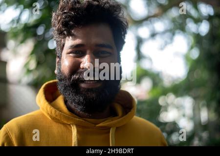 Handsome male model in a public park, Indian male model with green background Stock Photo