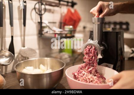 https://l450v.alamy.com/450v/2h9bdwa/mincer-machine-with-fresh-chopped-meat-at-home-kitchen-preparing-ground-meat-male-hands-closeup-2h9bdwa.jpg