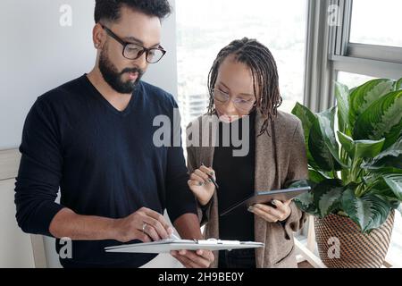 Serious business team discussing data in reports on clipboard and analyzing company performance Stock Photo