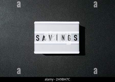Lightbox board on a black background with the words SAVINGS in black letters. Stock Photo