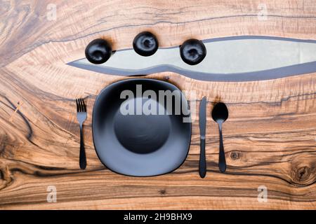 Black plate with black cutlery on a handmade epoxy resin table Stock Photo