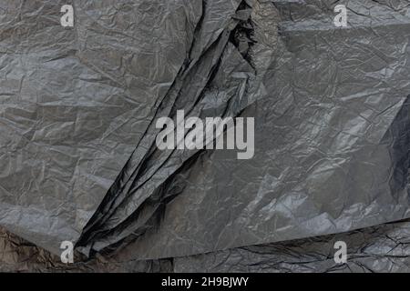Crumpled black kraft paper for gift wrapping or packaging. Close up, texture background, pollution and recycling concept Stock Photo