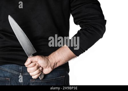 Foto de Man hide knife behind back in dark background do Stock