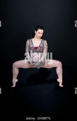 Young flexible Woman in her 20's, nine months pregnant. on black background. Model release available Stock Photo