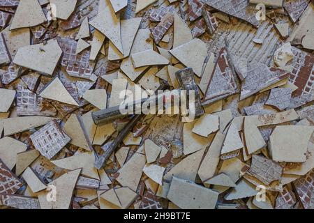 A kitchen floor covered with broken floor tiles a hammer and a chisel. Stock Photo