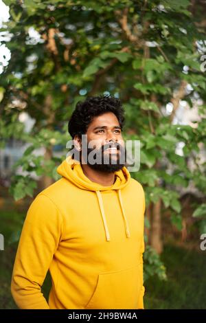 Handsome male model in a public park, Indian male model with green background Stock Photo