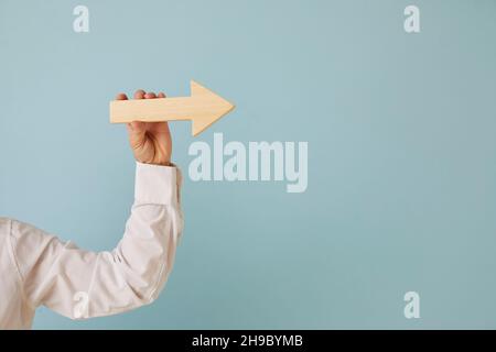 Businessman holding an arrow in his hand on a blue background with text copy space Stock Photo