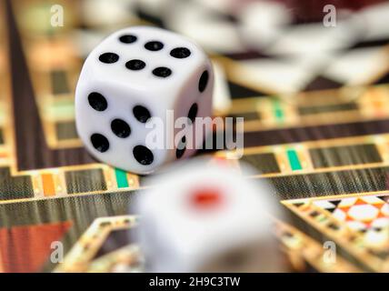 Close up with selective focus of dice on a colorful game board for a game of chance Stock Photo