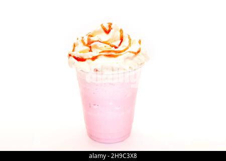 Strawberry milk shake with syrup drizzled on whipped cream in a plastic disposable cup. Stock Photo