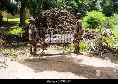 Two little black African brothers piling bunches of wood for charcoal production Stock Photo