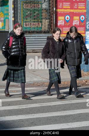 3 orthodox Jewish students dressed similarly, return from school on a Friday afternoon to prepare for the Sabbath. On Lee Avenue in Brooklyn, New York Stock Photo