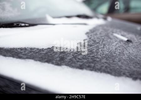 Hood of car is snow-covered in the cold in beautiful snowflakes. Close-up shot Stock Photo