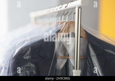 Clothes in plastic bags hanging on hanger in laundry closeup Stock Photo