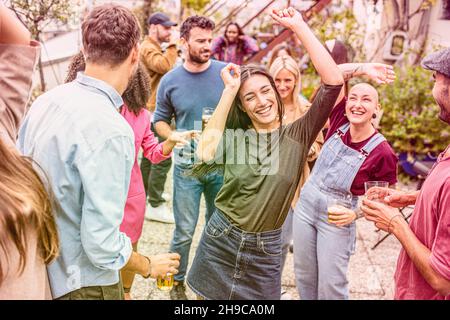 beautiful women and men dancing at party on a terrace, outdoor dancing celebration, young adult people having fun, smiling and laughing together Stock Photo