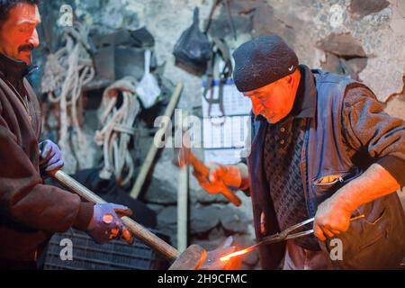 Kars,Turkey - 01-23-2016:Two old blacksmith working metal with hammer on the anvil in the forge,Kars province Stock Photo